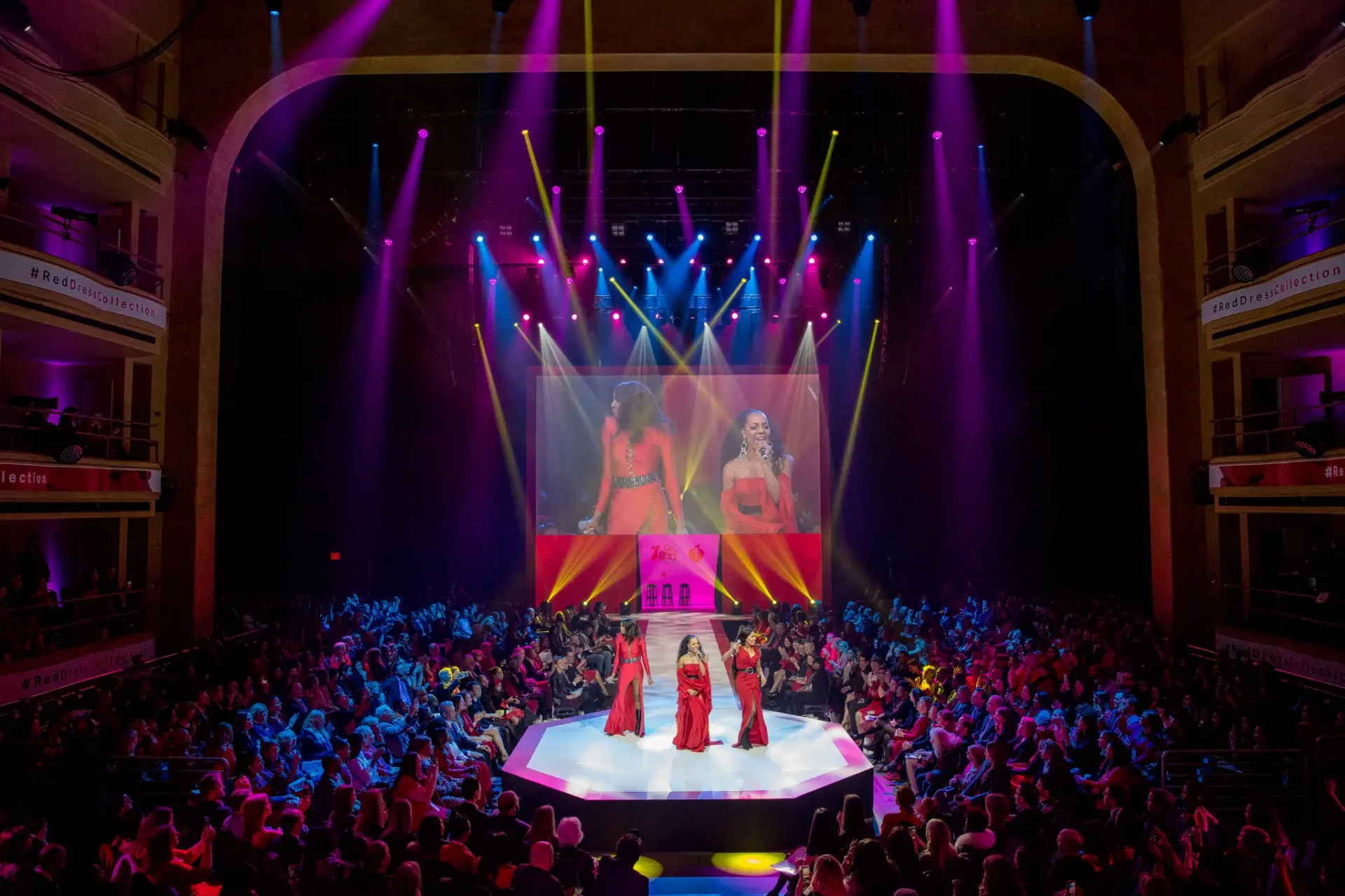 Fashion show with models on runway, audience attentively seated, and colorful stage lights Fashion show with models on runway, audience attentively seated, and colorful stage lights